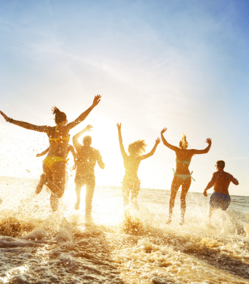 Sunset shadow of group of 5 people running into the ocean with small waves
